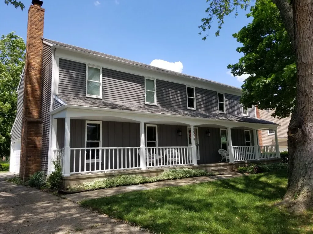 Gray house with white front porch after a full exterior repaint